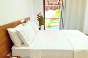 a white bed with white pillows and a window at Linda Casa no coração do Centro Histórico in Porto Seguro