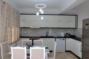 a kitchen with a glass table and white cabinets at Loris Apartment in Sarandë