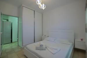 a white bedroom with a bed and a mirror at Loris Apartment in Sarandë