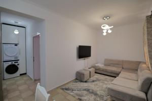 a living room with a couch and a tv at Loris Apartment in Sarandë +8 photos