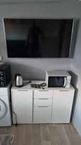 ein weißer Schrank mit einem großen Fernseher an der Wand in der Unterkunft Bien etre in Drancy + 4 Fotos