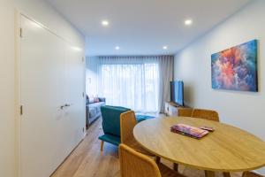 a living room with a table and a room with a couch at Modern 2 Bed 2 Bath Opposite Hagley Park in Christchurch