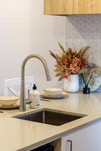 a kitchen counter with a sink and flowers in a vase at Modern 2 Bed 2 Bath Opposite Hagley Park in Christchurch
