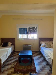 una camera da letto con due letti e un tavolo di Une belle maison avec jardin au centre Moulay bousselham a Moulay Bousselham