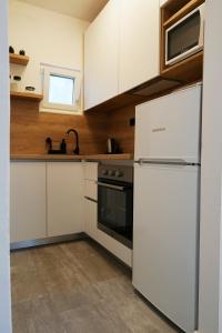 a kitchen with white cabinets and a refrigerator at Apartments with parking space Marusici, Omis - 657 in Mimice +13 photos