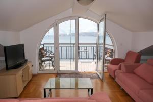 a living room with a couch and a tv and a balcony at Apartments with parking space Senj - 15376 in Senj