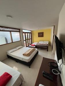 a bedroom with two beds and a desk and a television at Hotel San Juan Guatape in Guatapé