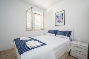 ein weißes Schlafzimmer mit einem Bett und einem Fenster in der Unterkunft Apartments by the sea Stara Novalja, Pag - 21662 in Stara Novalja