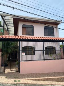 a pink and white house with a gate at Apartamento Caribe Rosa in Puerto Limón