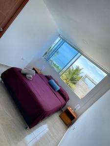 a bedroom with a purple bed and a large window at Hotel La Yarolina SAS in Cartagena de Indias