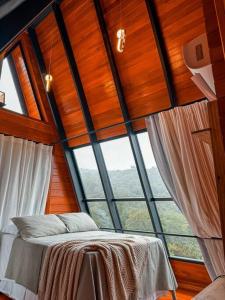 een bed in een kamer met een groot raam bij Chalé e refúgio dos sonhos! Conheça o Kleines Paradies in Massaranduba