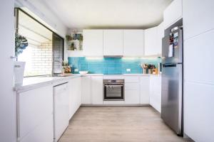 eine Küche mit weißen Schränken und einem Kühlschrank in der Unterkunft Peaceful River Front Escape Short walk to Ocean St in Maroochydore