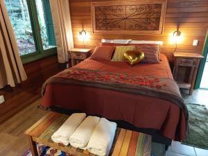 a bedroom with a large bed with towels on it at Chalés Serras House Casa Verde e Casa Laranja in São Francisco de Paula