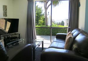 ein Wohnzimmer mit einem Ledersofa und einem Glastisch in der Unterkunft Alpine Nook in Lake Tekapo