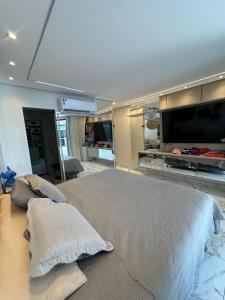 a bedroom with a large bed and a flat screen tv at Casa Perola do Tapajós - Quartos privativos in Santarém