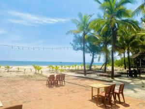 a table and chairs on the beach with palm trees at Tam Thanh Natural Beach Resort in Tam Ky