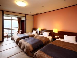 a hotel room with three beds and a balcony at Nagasaki Nisshokan in Nagasaki