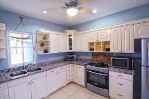 a large kitchen with white cabinets and a window at Casa Brisa, Gran Pacifica in Managua +2 photos