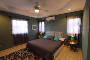 a bedroom with a bed with green walls and windows at Casa Brisa, Gran Pacifica in Managua