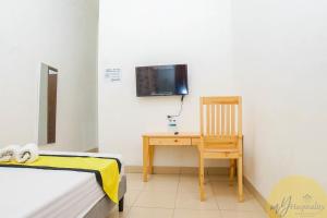 a bedroom with a desk and a tv and a chair at Anggrek Guest House Cirebon in Tangkil