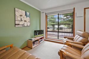 a living room with a couch and a tv and a window at Eastern Beach Unit 5 in Port Fairy