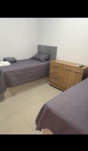 a bedroom with two beds and a wooden dresser at Clube Araguaia in Caseara