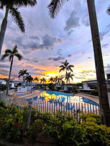 a swimming pool with palm trees and a sunset at Casa Premium Las Palmas San Jeronimo in San Jerónimo