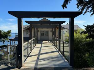 una pasarela de madera a una casa con techo negro en Sahhali On The Bluffs East Room, en Pender Island