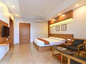 a hotel room with a bed and a chair and a table at Maharani Hotel in Kozhikode