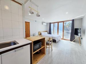 a kitchen and living room with a bed in a room at Greenside Pension in Seogwipo
