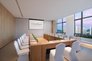 a conference room with a long table and white chairs at Citadines Yazhou Bay Sanya in Sanya