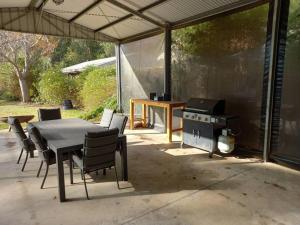 a patio with a table and chairs and a grill at Homefield Homestead Halls Gap in Halls Gap