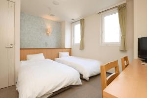 a bedroom with two beds and a desk and a television at Kur and Hotel Isawa in Fuefuki