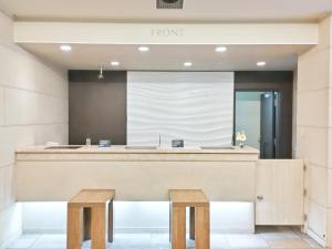 青森市にあるホテルルートイン青森駅前の木製のスツール2脚付きの建物内のフロントデスク