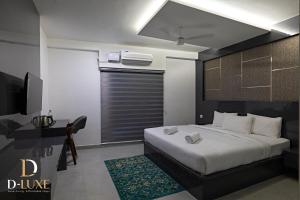 a bedroom with a large bed and a television at D-Luxe Hotel in Ernakulam