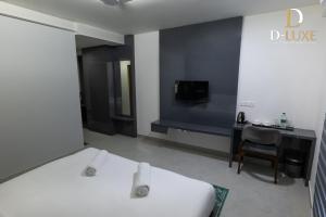 a bedroom with a bed and a desk and a tv at D-Luxe Hotel in Ernakulam +25 photos