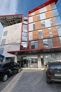 two cars parked in front of a building at D-Luxe Hotel in Ernakulam