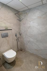 a bathroom with a white toilet and a marble wall at D-Luxe Hotel in Ernakulam