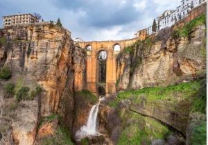 a bridge with a waterfall in front of a mountain at Casa Lucero in Ronda