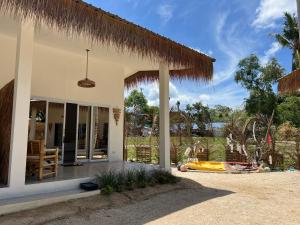 a house with a porch with a pineapple roof at Sea Love Beach Bar & Bungalows in Ban Tai