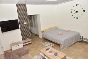a bedroom with a bed and a clock on the wall at Dora Apartman in Bačka Topola