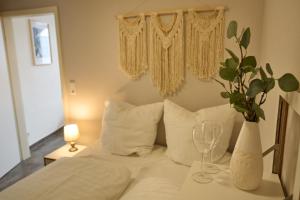 a white bed with a vase and glasses on a table at DTV-zertifizierte Ferienwohnung Kleine Moselruhe - zentral, für 3 Personen, Parkplatz & WLAN in Traben-Trarbach