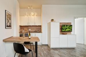 a kitchen with white cabinets and a wooden table and chairs at DTV-zertifizierte Ferienwohnung Kleine Moselruhe - zentral, für 3 Personen, Parkplatz & WLAN in Traben-Trarbach