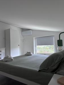 a white bedroom with a large bed with a window at SaDomoSicula UJazzu in Ragusa +2 photos