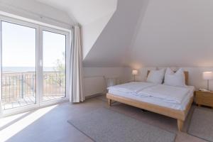 a white bedroom with a bed and a large window at Haus NÖCK in Wustrow