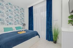 una camera da letto con un letto blu e tende blu di Klifowa Resort Apartment SPA & Fitness Near the beach in Rewal by Renters Prestige a Rewal