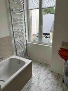 a white bathroom with a tub and a window at Maison de ville conviviale avec terrasse in Lanester