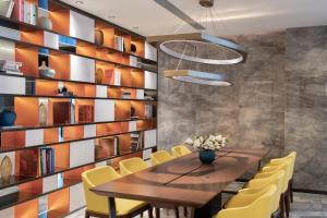 a dining room with a wooden table and yellow chairs at 东莞大朗希尔顿欢朋酒店 in Huangcaolang