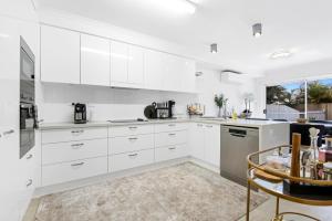 a white kitchen with white cabinets and appliances at Shearwater Luxury in Coffs Harbour