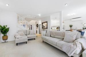 a living room with white furniture and a staircase at Shearwater Luxury in Coffs Harbour +27 photos